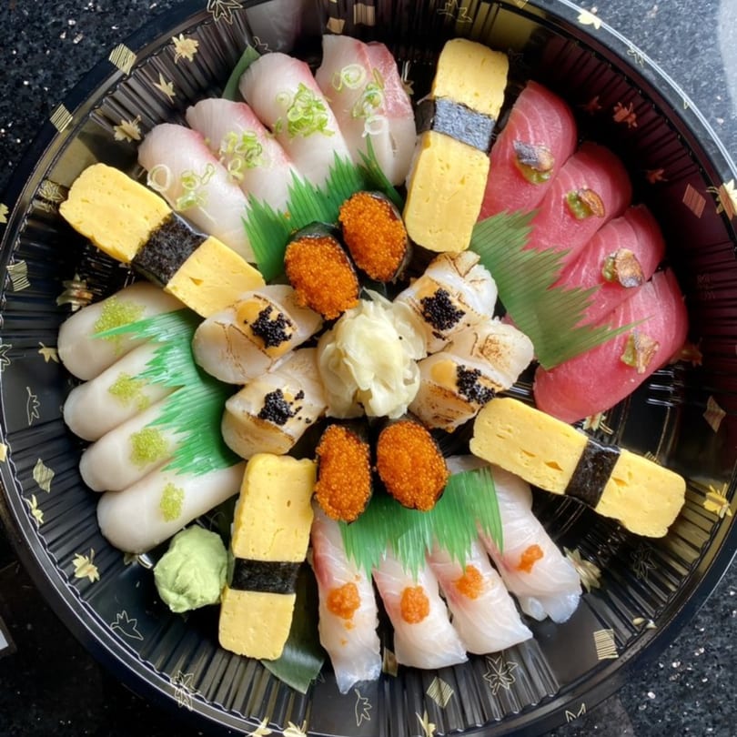 A large black platter of assorted Fuumi sushi, including nigiri, tamago, and roe.