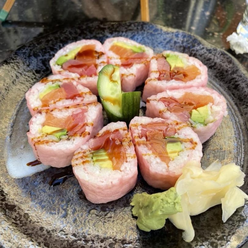 Eight pieces of Fuumi's pink sushi rolls with salmon, avocado, and sauce, served with ginger and wasabi.